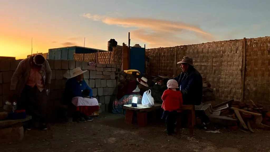 Residents gather for dinner in darkness, illuminated only by a solar-powered torch